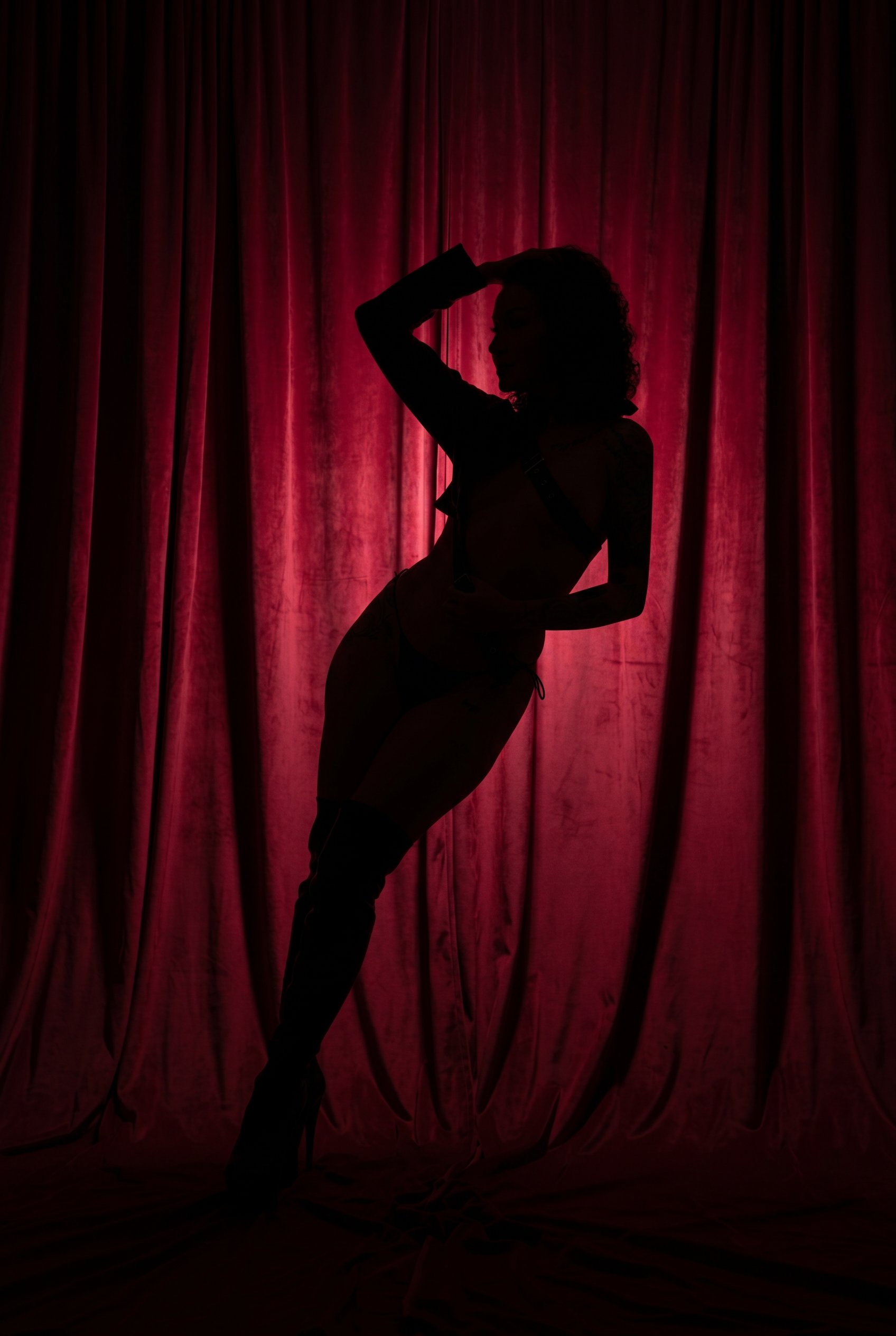 Dramatic silhouette of Goddess Lee against a red silk curtain